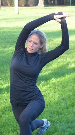 Angela mid-stretch in a kneeling lunge, outdoors in soft afternoon light