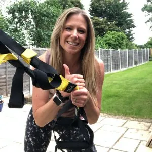 Angela working with TRX, smiling, outdoors